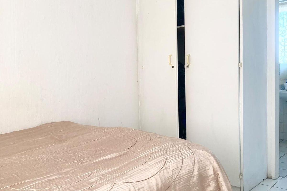 A bedroom featuring white walls, tiled flooring, and a built-in wardrobe with double doors.