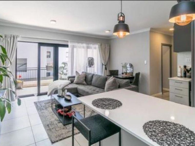 Modern open-plan living area featuring a kitchen island, tiled flooring, and sliding glass doors leading to a private balcony.