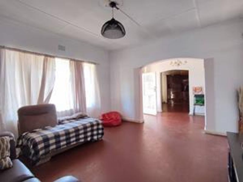 Spacious living area featuring an arched transition to an adjacent room, neutral walls, and tiled flooring throughout.