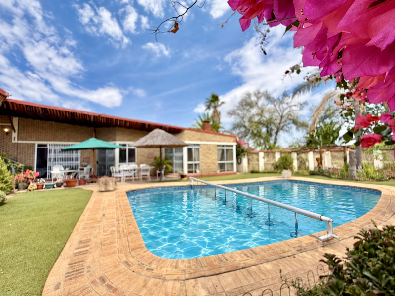 A well-maintained outdoor pool area featuring brick paving, a clear swimming pool, and direct access to the home via sliding glass doors.