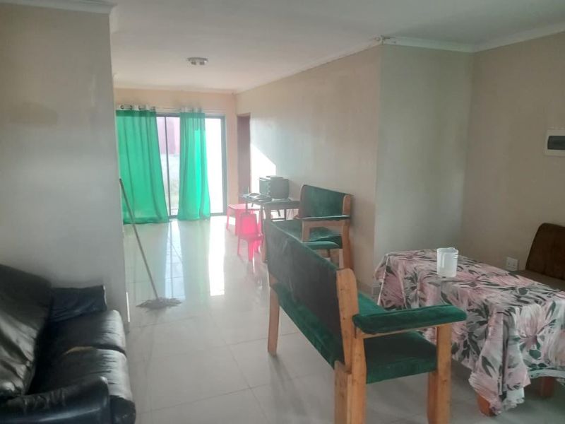 A living area featuring tiled flooring and a sliding glass door leading to the exterior, with visible wear on walls and ceiling finishes.