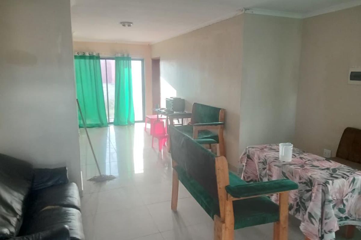 A living area featuring tiled flooring and a sliding glass door leading to the exterior, with visible wear on walls and ceiling finishes.