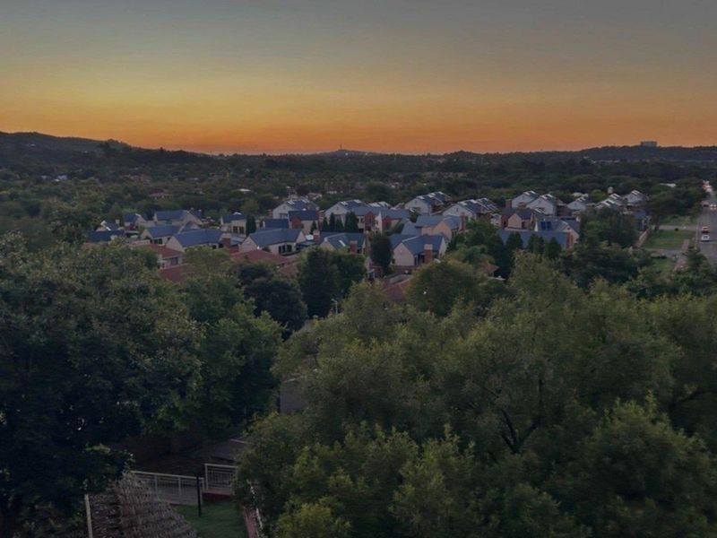 An elevated sunset view overlooking a residential neighborhood with lush greenery and suburban housing.