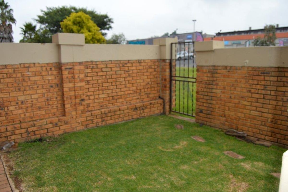 A small private rear garden area enclosed by a brick boundary wall with a metal pedestrian gate.