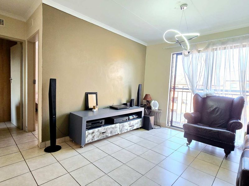 A living room featuring ceramic floor tiles, a modern pendant light, and a sliding door leading to a balcony.