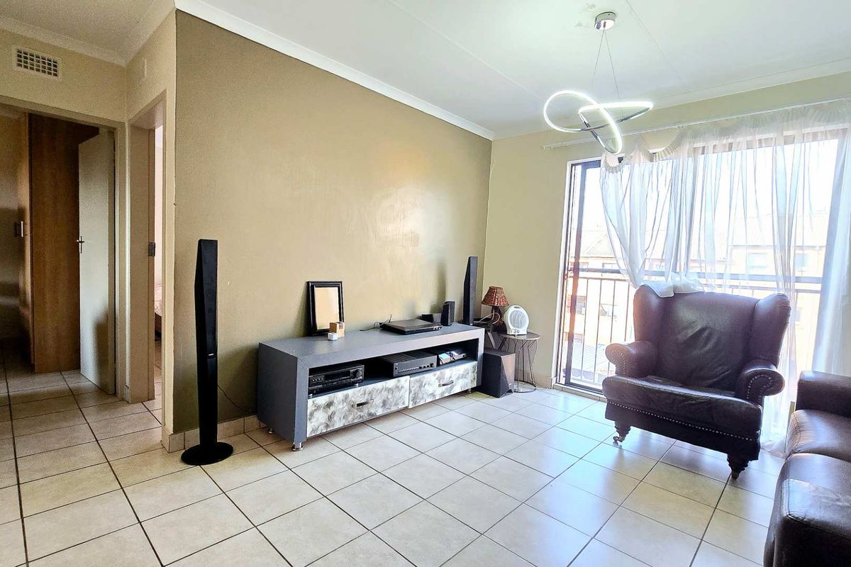 A living room featuring ceramic floor tiles, a modern pendant light, and a sliding door leading to a balcony.