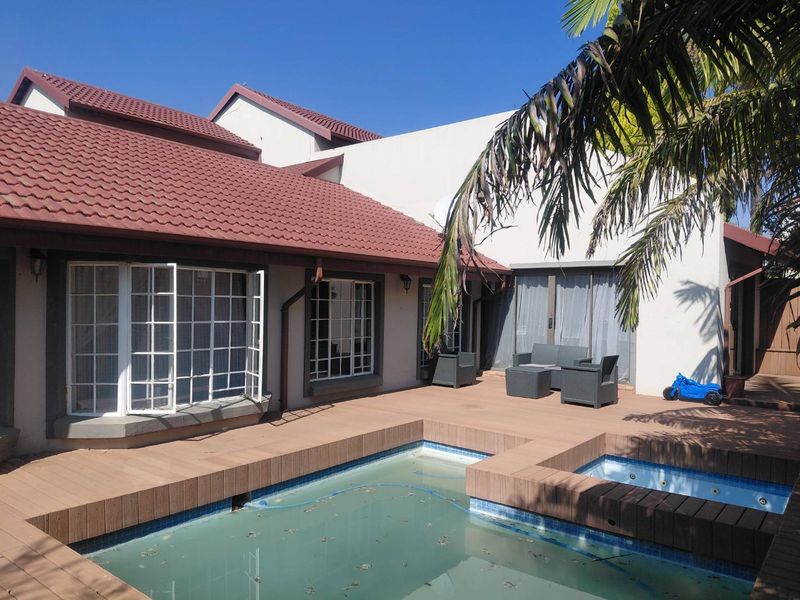 Outdoor pool area featuring a swimming pool, integrated spa, and timber decking, adjacent to the main house structure.