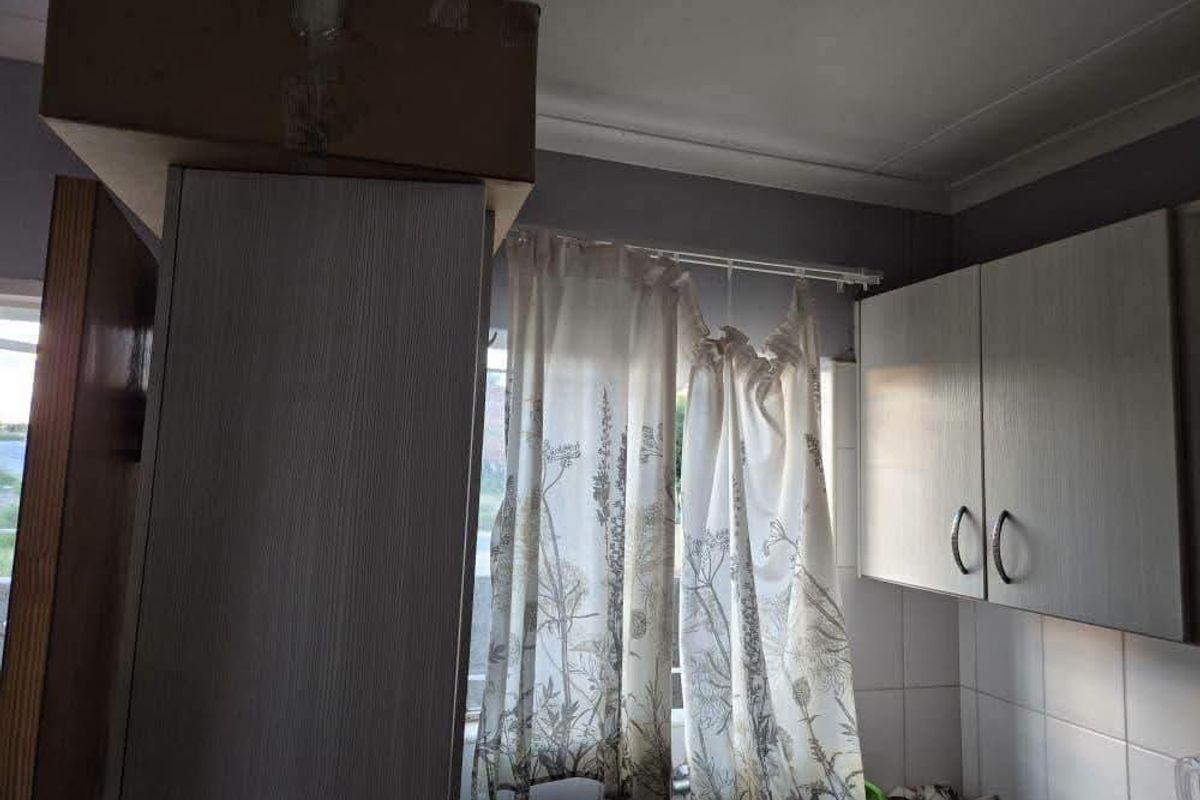 A kitchen area featuring built-in cabinetry and tiled splashbacks, currently showing signs of wear and an unfinished bulkhead section.