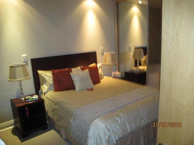 A bedroom featuring a built-in mirrored wardrobe and recessed lighting, providing a functional space with neutral finishes.