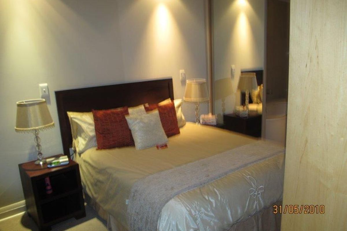 A bedroom featuring a built-in mirrored wardrobe and recessed lighting, providing a functional space with neutral finishes.