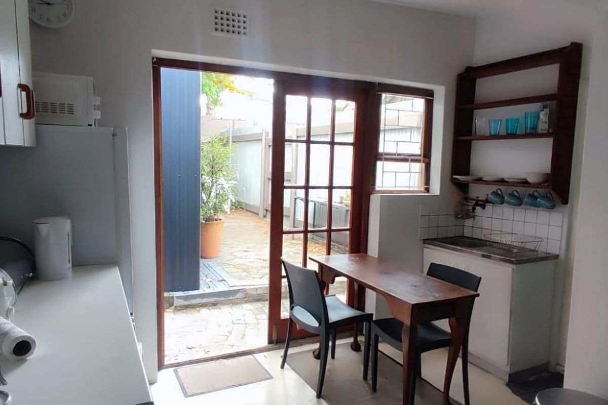 A functional kitchen featuring built-in cabinetry, a tiled backsplash, and direct access to an outdoor patio area through a timber-framed glass door.