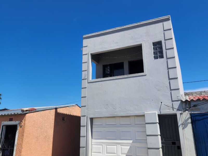 Front elevation of a two-story residential property featuring a garage, ground floor entrance, and an upper-level balcony.