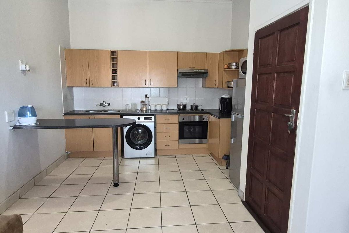 Functional kitchen featuring laminate cabinetry, built-in oven, extractor fan, tiled backsplash, and a breakfast bar, with tiled flooring throughout.
