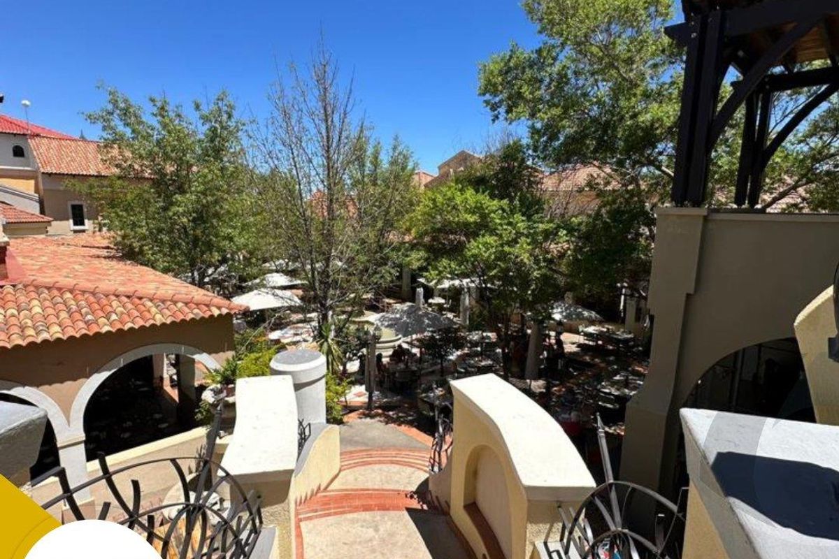 An elevated view looking down a terracotta tiled staircase with wrought iron railings, leading towards a landscaped courtyard area with outdoor seating.