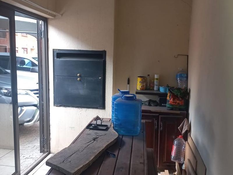 Covered patio area featuring a built-in braai, tiled flooring, and sliding door access to the exterior.