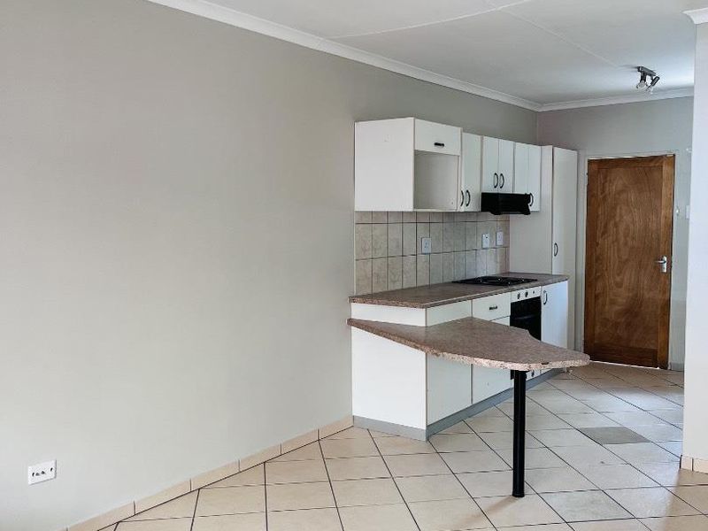 A functional kitchen featuring built-in cabinetry, a breakfast bar, tiled flooring, and integrated appliances, offering a clean and neutral space ready for updates.