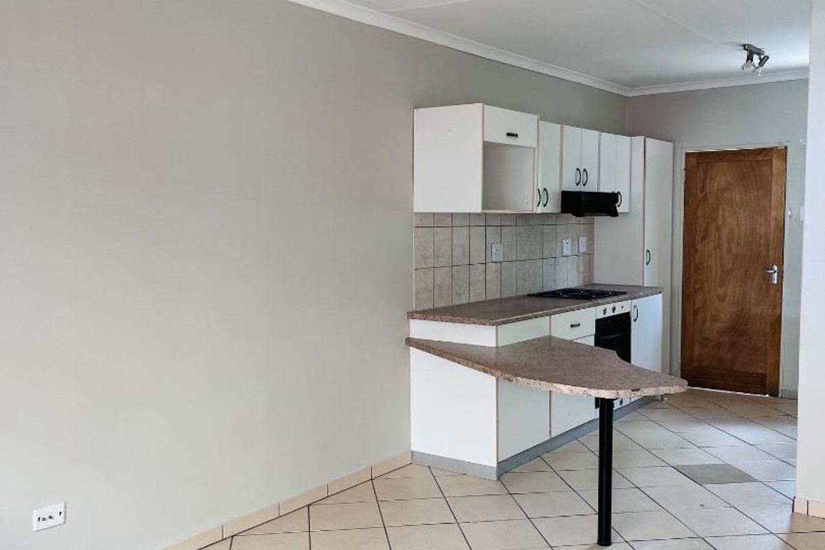A functional kitchen featuring built-in cabinetry, a breakfast bar, tiled flooring, and integrated appliances, offering a clean and neutral space ready for updates.