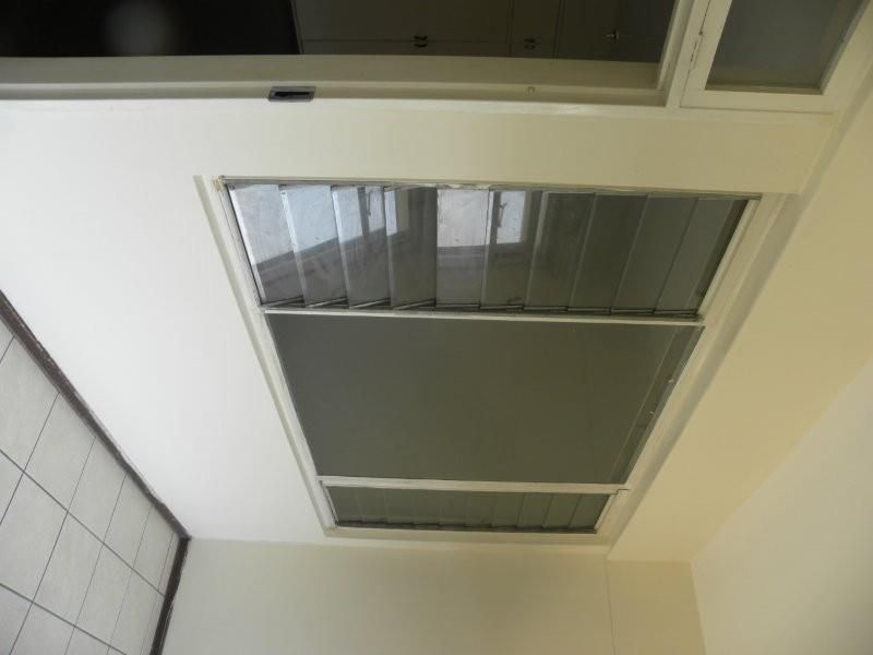 An interior view showing tiled flooring and louvered windows within a vacant space.