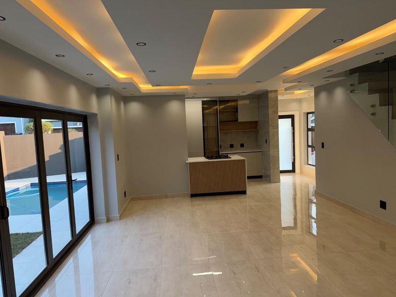 Modern open-plan living area featuring high-end porcelain tiling, a sophisticated coffered ceiling with ambient lighting, and seamless access to the pool area.