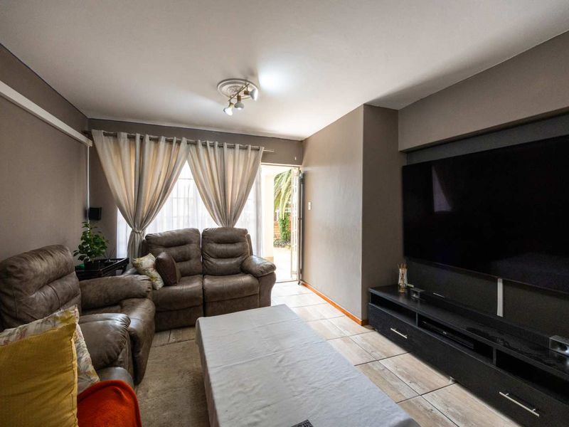 A comfortable living room featuring tiled flooring, a ceiling rose, and direct access to an outdoor area through a sliding door.