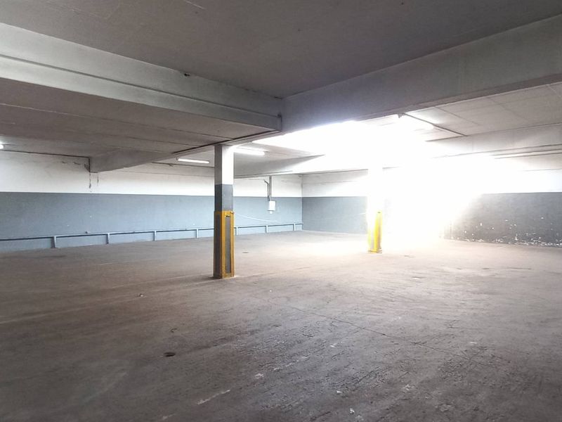 A spacious, open-plan industrial utility area featuring concrete flooring, structural support columns, and overhead fluorescent lighting.