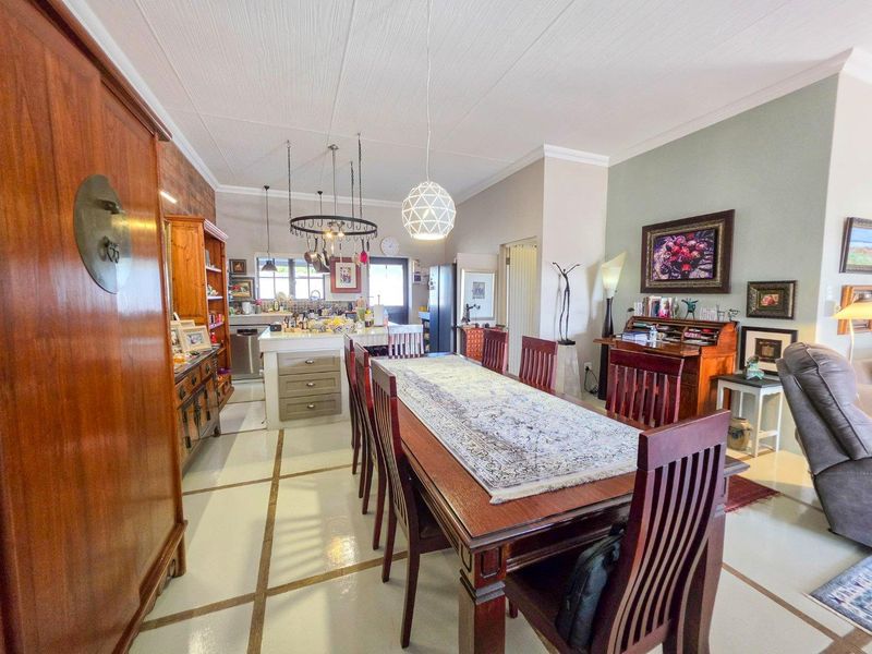 Spacious open-plan living and dining area featuring a central kitchen island, pendant lighting, and tiled flooring, creating a functional and connected home layout.