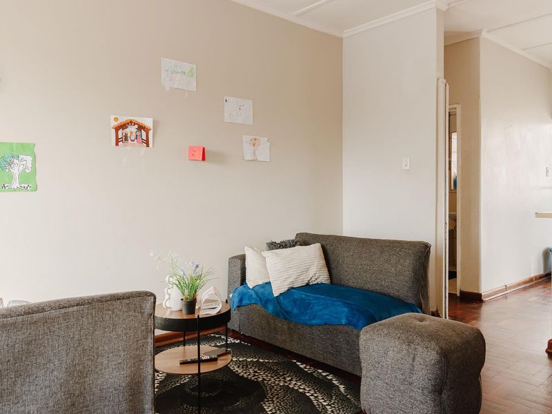 A living room area featuring classic parquet flooring and coved ceiling details, providing a neutral foundation for interior design updates.