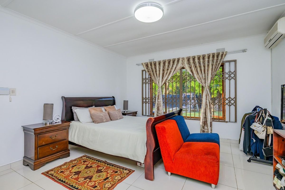 A bedroom featuring tiled flooring, a split-system air conditioner, and a window fitted with a security gate.