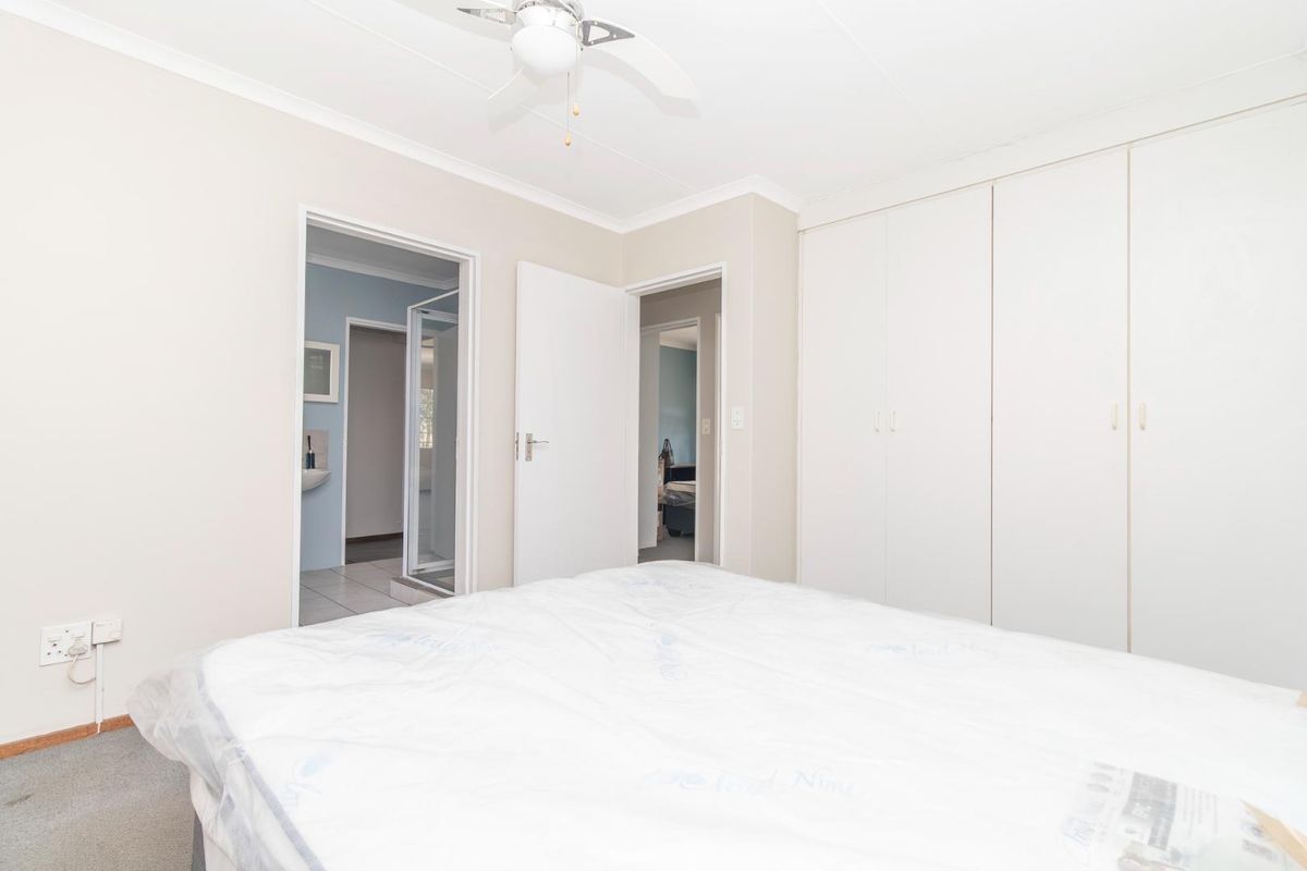 A bedroom featuring built-in cupboards, a ceiling fan, and an en-suite bathroom with a shower.