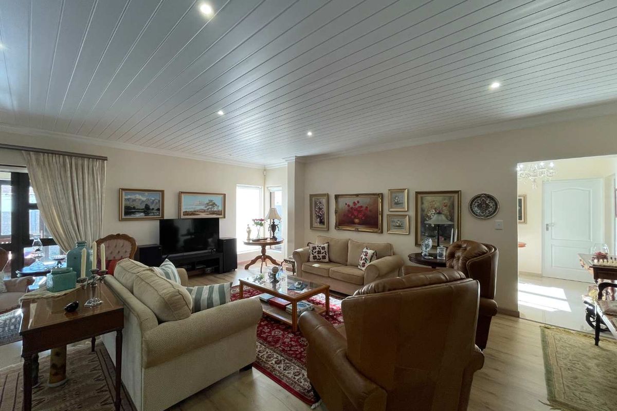 Spacious living room featuring a white tongue and groove ceiling, recessed downlights, and light-toned laminate flooring.
