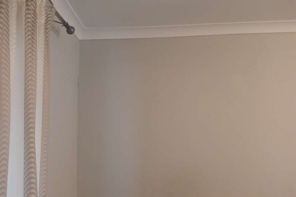 A view of a bedroom corner featuring coved ceiling cornicing and neutral wall finishes.