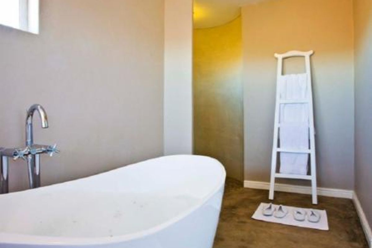 A modern bathroom featuring a freestanding soaking tub with chrome floor-mounted faucet and polished concrete flooring.