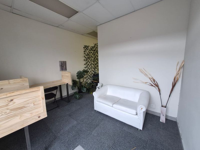 A small office space featuring carpeted flooring and a suspended ceiling with visible wear on the ceiling tiles.