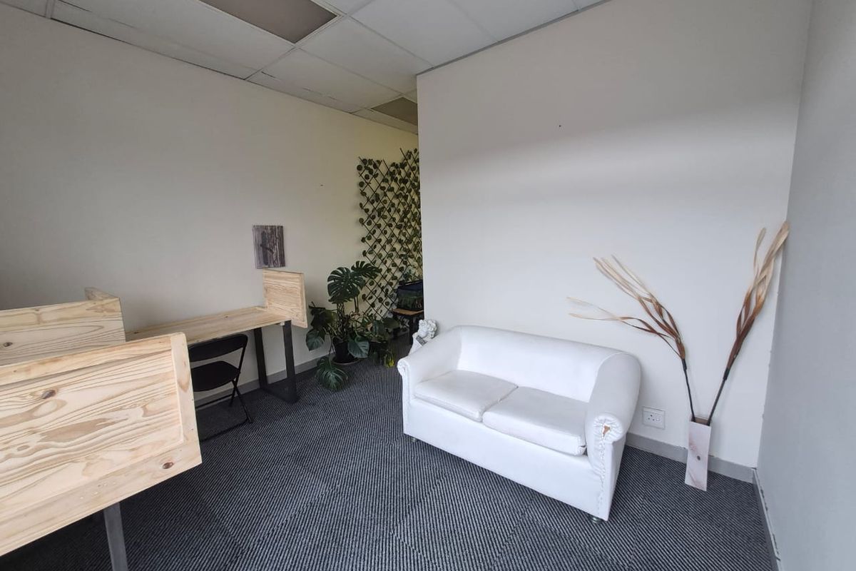 A small office space featuring carpeted flooring and a suspended ceiling with visible wear on the ceiling tiles.