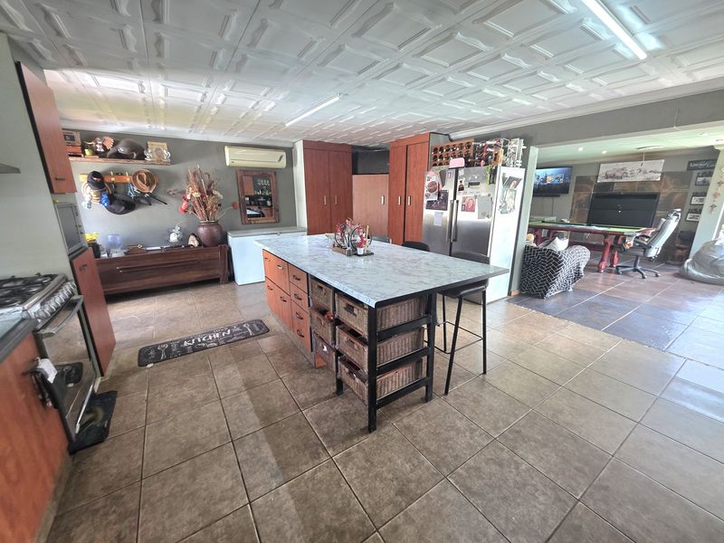 Spacious open-plan kitchen and living area featuring a central island, tiled flooring, and a distinctive coffered ceiling design.
