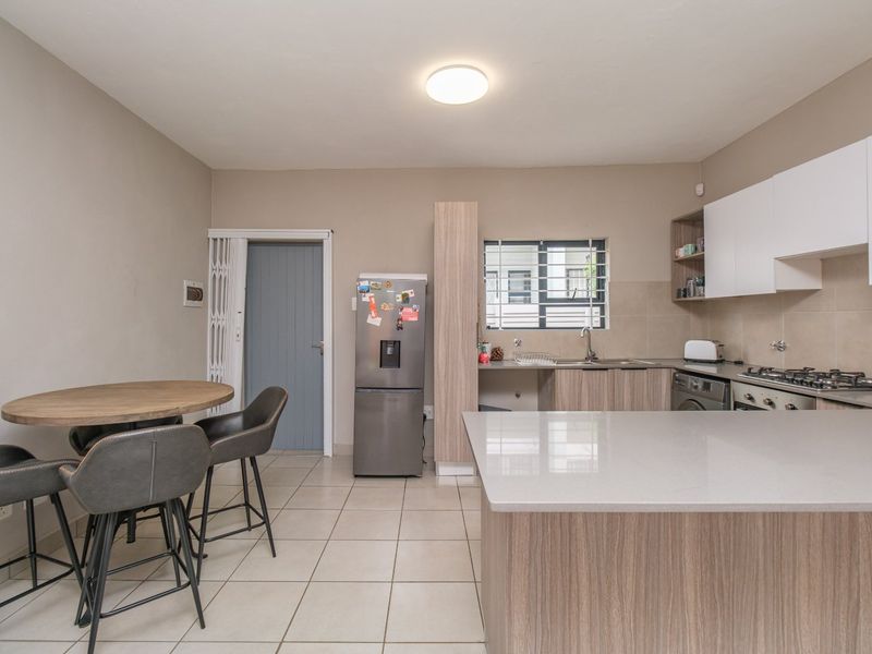 Modern open-plan kitchen featuring stone countertops, ample cabinetry, gas hob, and integrated appliances, seamlessly flowing into a casual dining area.