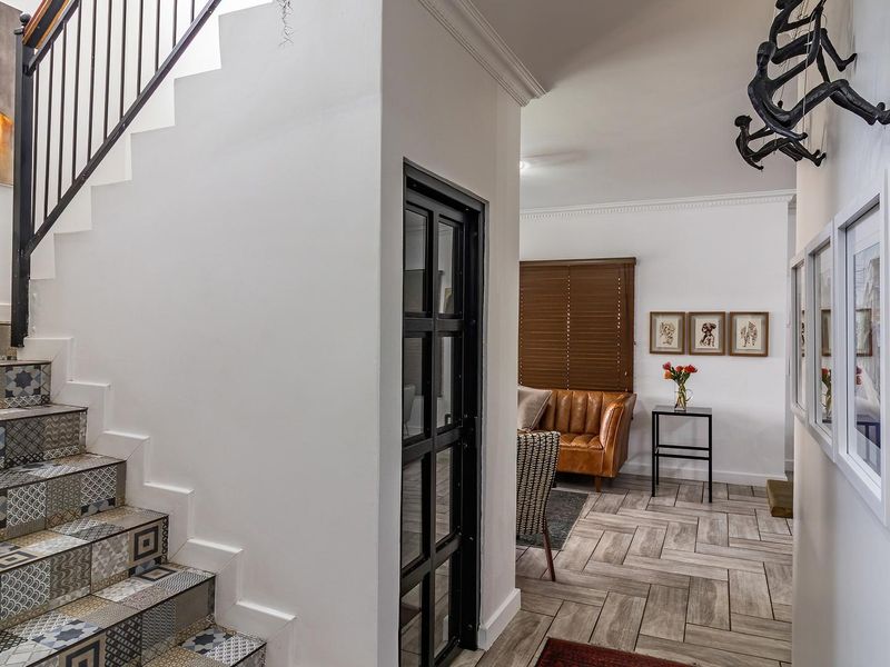 Welcoming entrance hall featuring a striking staircase with patterned tile risers, wrought iron balustrade, and seamless flow into the adjacent living area.