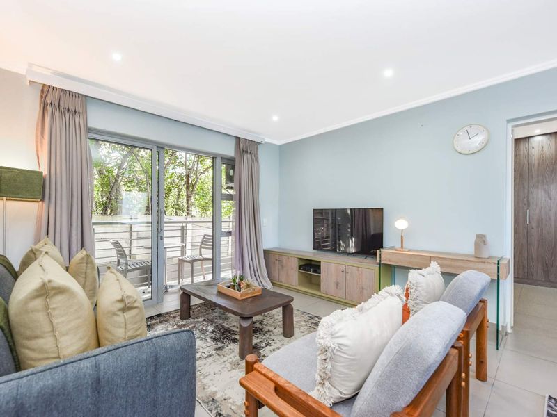 A bright and well-maintained living room featuring tiled flooring, recessed lighting, and a large sliding glass door providing access to an outdoor balcony area.