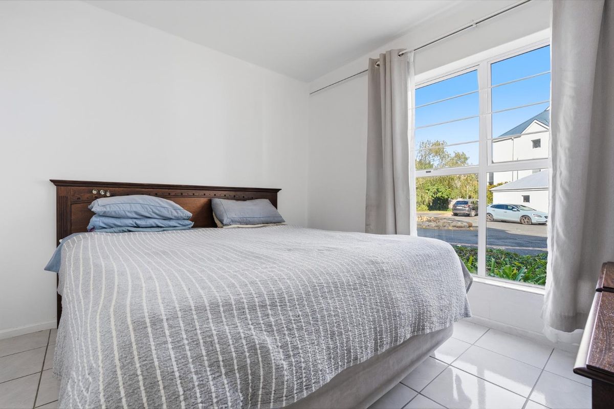 A bright bedroom featuring tiled flooring and a large window that allows for ample natural light.