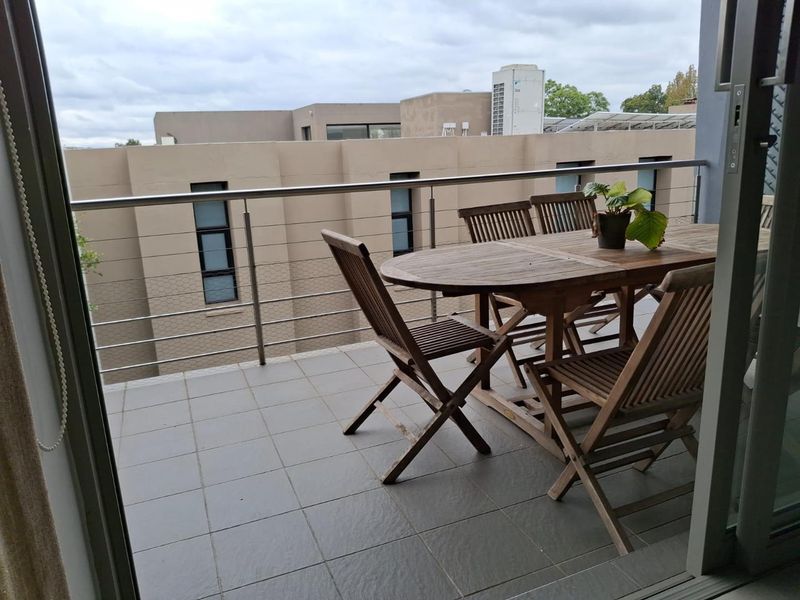 A private balcony featuring tiled flooring and a modern stainless steel balustrade, offering an outdoor space accessible via sliding glass doors.