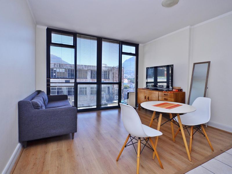 Open-plan living and dining area featuring large floor-to-ceiling windows that provide ample natural light and urban views.