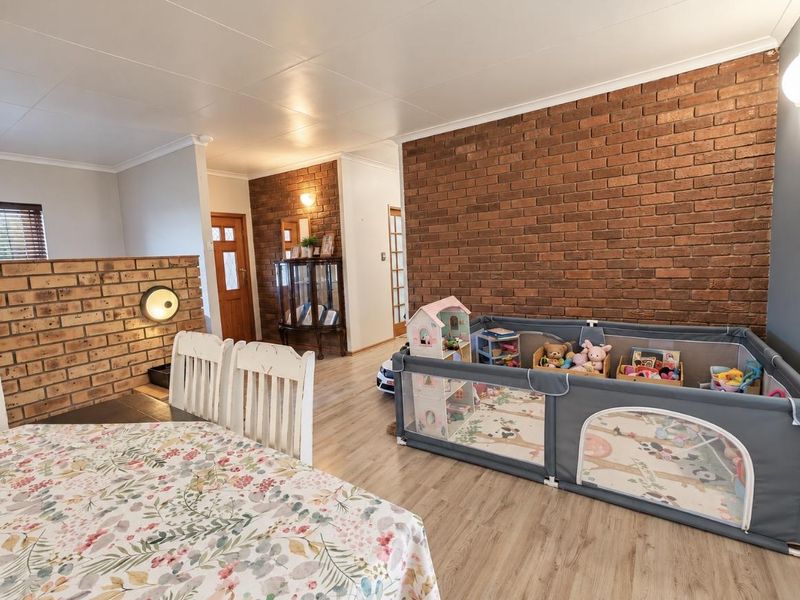 Open plan living area featuring a prominent exposed brick feature wall and durable laminate flooring, creating a warm and textured interior space.
