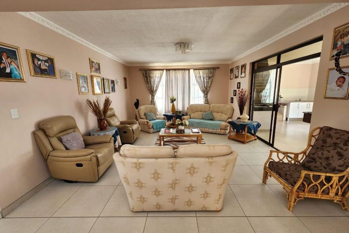 A spacious living room featuring neutral tiled flooring, decorative ceiling cornices, and a large sliding glass door providing access to an adjacent area.