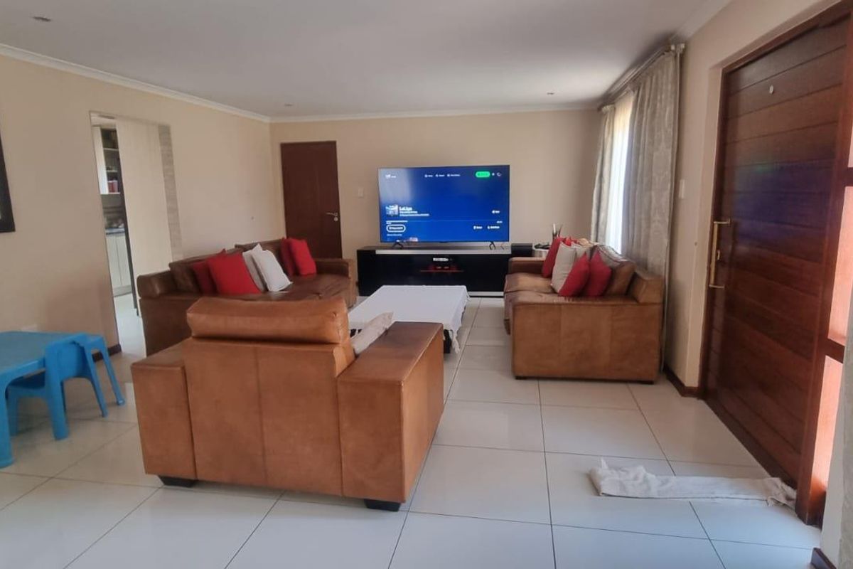 Spacious living room featuring large format floor tiles, recessed downlighting, and a solid timber entrance door, creating a bright and functional open-plan living space.