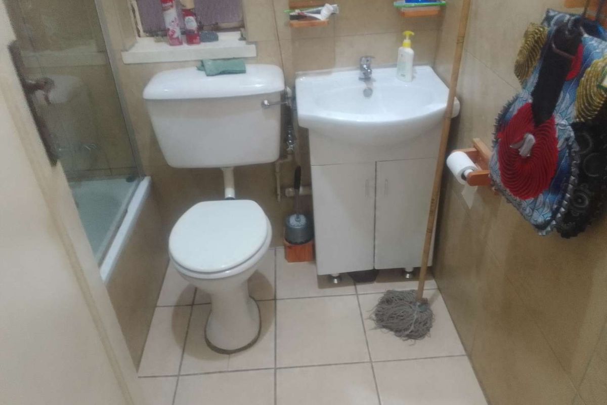 Compact bathroom featuring a toilet, vanity basin, and a shower enclosure with tiled finishes throughout.