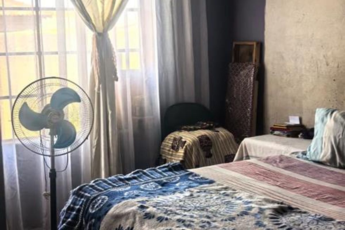 A bedroom featuring tiled flooring and decorative ceiling tiles, requiring cosmetic updates to the wall finishes.