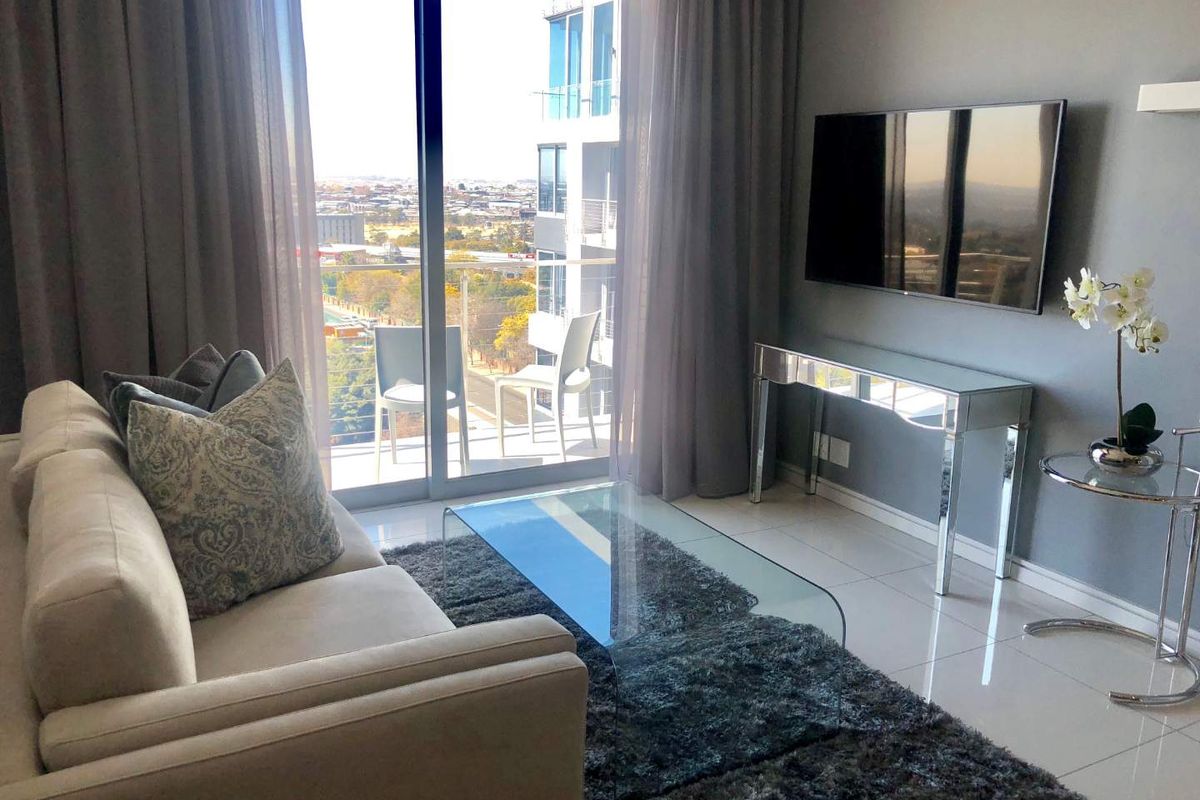 Modern living room featuring large sliding glass doors that open onto a balcony, providing ample natural light and expansive city views.