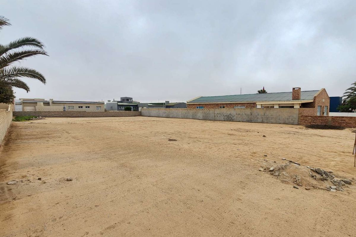 A vacant residential plot featuring a sandy surface and enclosed by perimeter boundary walls, offering a clear space for future development.