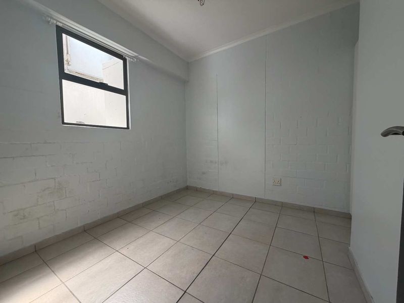 An empty bedroom featuring tiled flooring and painted brick walls, providing a blank canvas for potential interior design and furnishing.