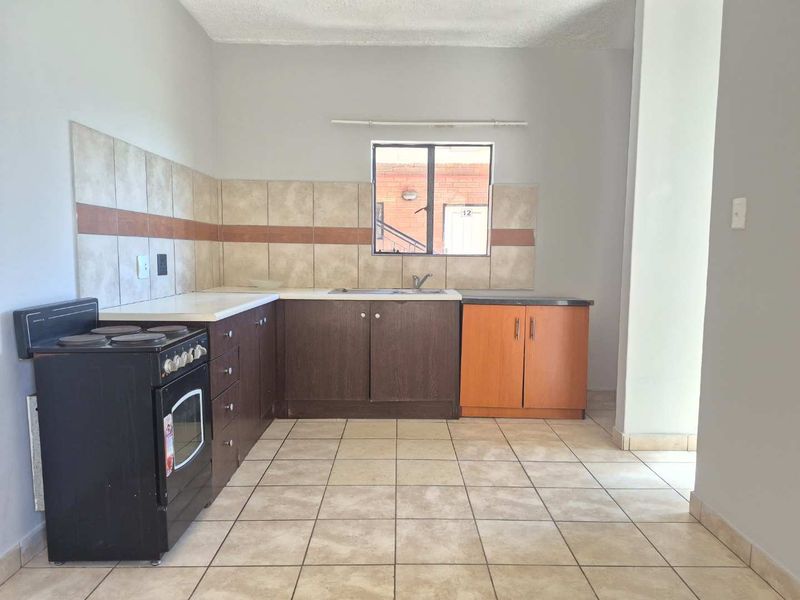 A functional kitchen featuring tiled flooring, a tiled backsplash, built-in cabinetry, and a stainless steel sink, offering a clean and practical layout.